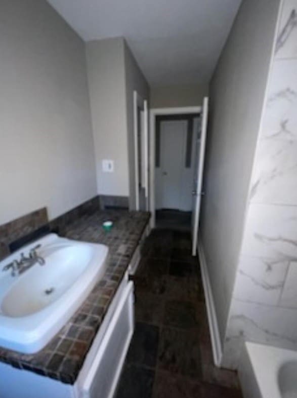 full bathroom with a washtub, baseboards, and vanity