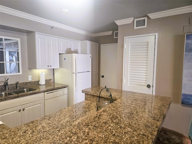 kitchen featuring a sink, dark stone countertops, crown molding, visible vents, and white appliances