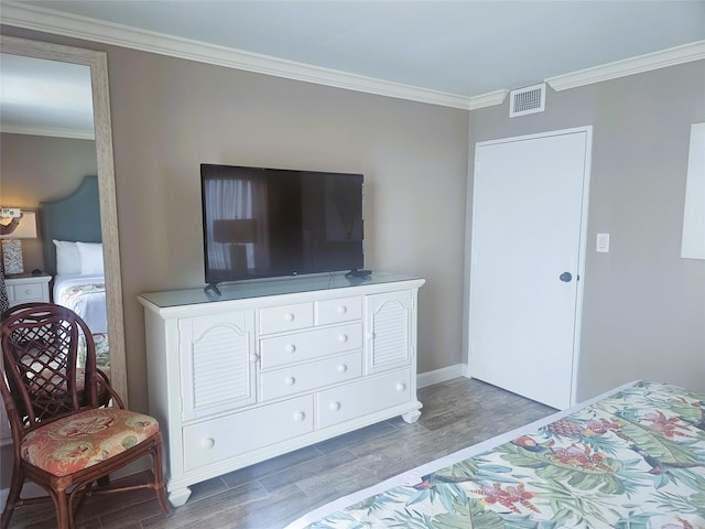 bedroom featuring ornamental molding, visible vents, wood finished floors, and baseboards