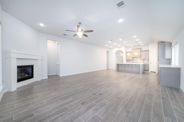 10419 Rigel Ridge Way, Richmond, TX 77406 - unfurnished living room featuring a ceiling fan, a glass covered fireplace, recessed lighting, light wood-style flooring, and baseboards