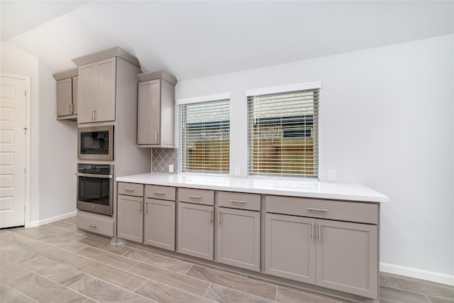 10419 Rigel Ridge Way, Richmond, TX 77406 - kitchen featuring stainless steel appliances, gray cabinets, light countertops, and vaulted ceiling