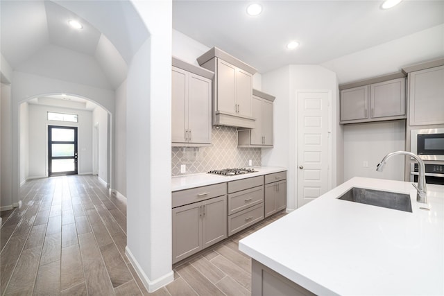 10419 Rigel Ridge Way, Richmond, TX 77406 - kitchen featuring a sink, gray cabinetry, arched walkways, lofted ceiling, and stainless steel appliances