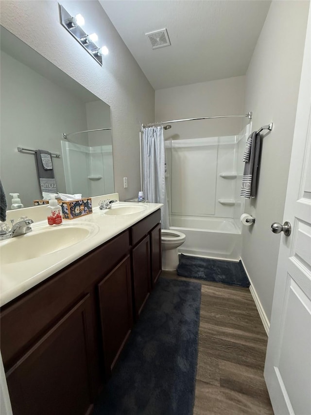 bathroom featuring double vanity, wood finished floors, visible vents, a sink, and shower / tub combo