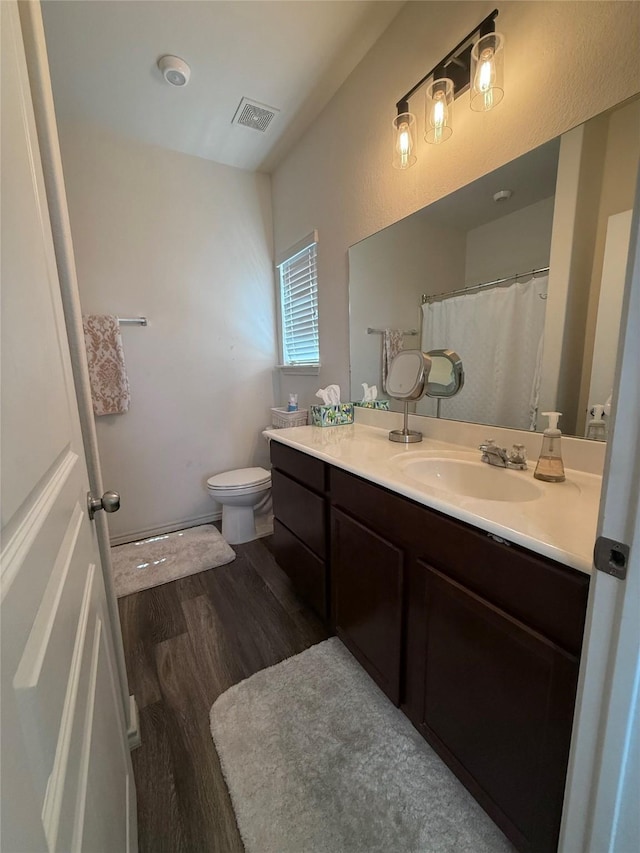 bathroom featuring wood finished floors, visible vents, toilet, and vanity