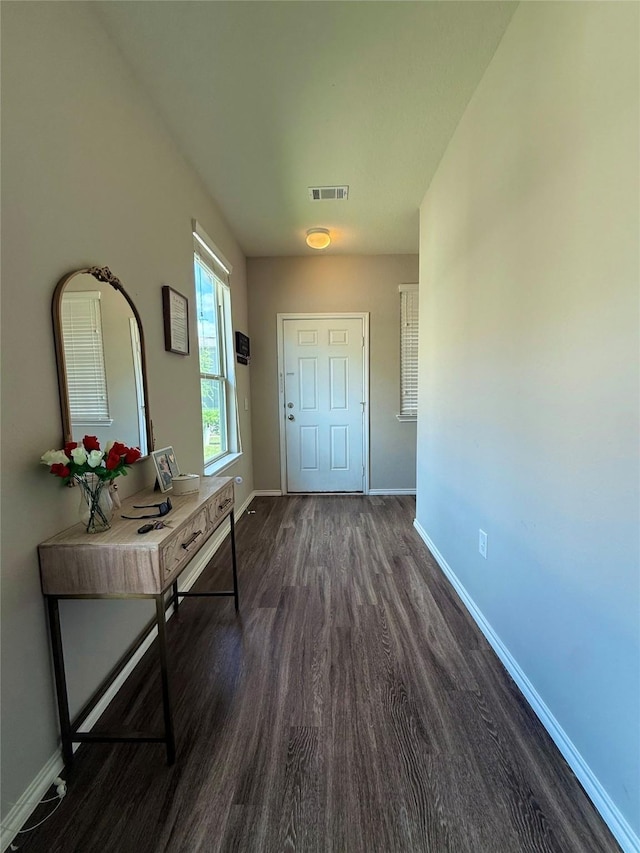 doorway to outside with baseboards, visible vents, and dark wood-type flooring