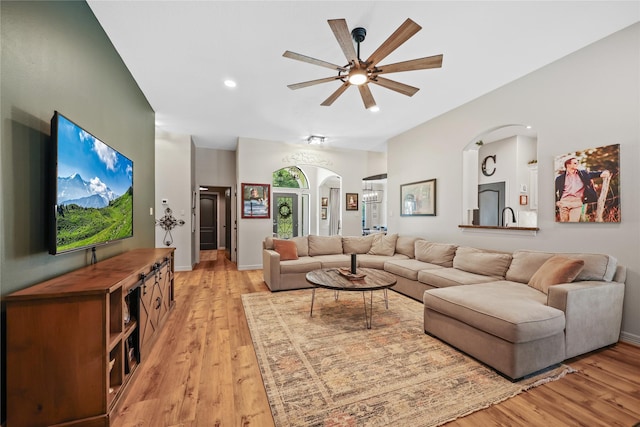 living area featuring arched walkways, ceiling fan, recessed lighting, and light wood-style floors