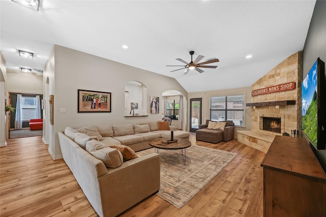 living area with arched walkways, light wood-style flooring, and ceiling fan