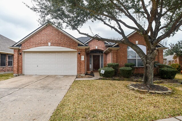view of front facade with a front lawn, brick siding, driveway, and a garage