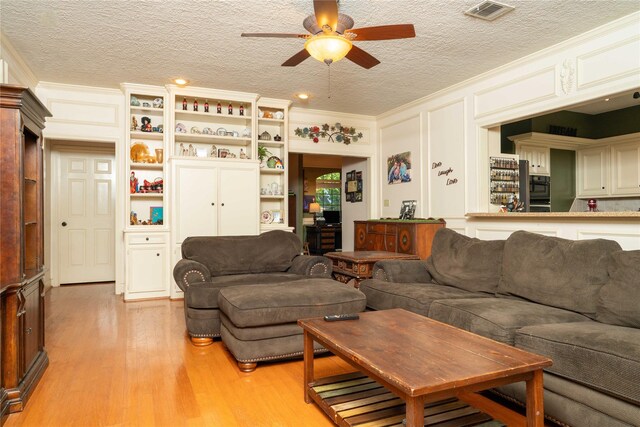 13710 Casaba Ct, Cypress, TX 77429 - living room with light wood-style flooring, a textured ceiling, visible vents, ceiling fan, and crown molding