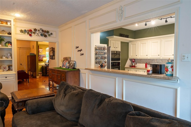13710 Casaba Ct, Cypress, TX 77429 - kitchen featuring white cabinets, wood finished floors, ornamental molding, black oven, and a textured ceiling