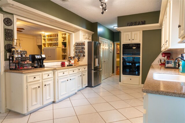 13710 Casaba Ct, Cypress, TX 77429 - kitchen featuring a sink, a textured ceiling, black appliances, light tile patterned floors, and white cabinets
