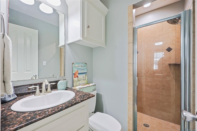 bathroom featuring toilet, a shower stall, and vanity