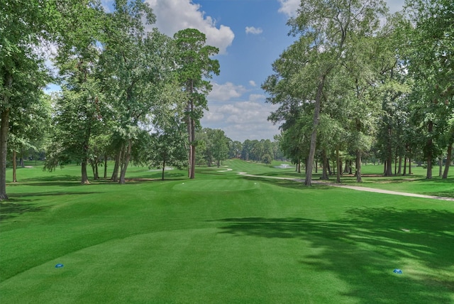 view of property's community with a lawn and view of golf course