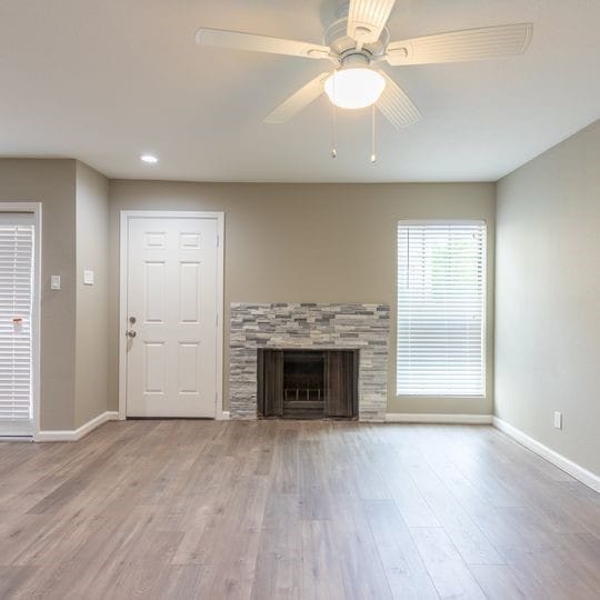unfurnished living room featuring a fireplace, wood finished floors, baseboards, and ceiling fan