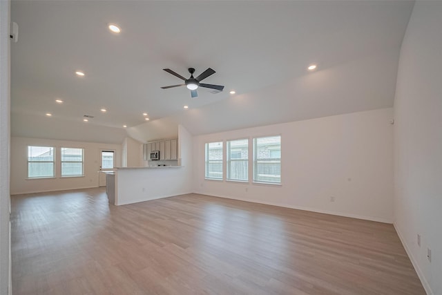 unfurnished living room with light wood finished floors, vaulted ceiling, and a healthy amount of sunlight