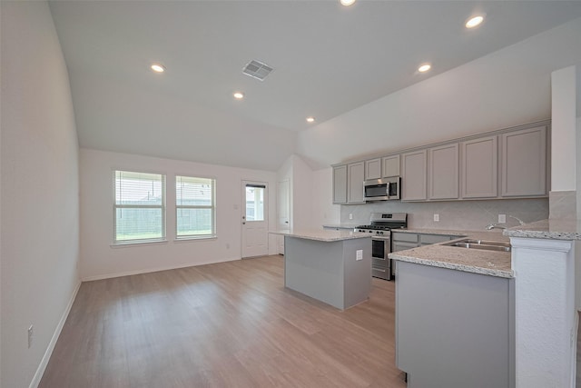 kitchen with a center island, gray cabinets, stainless steel appliances, lofted ceiling, and visible vents