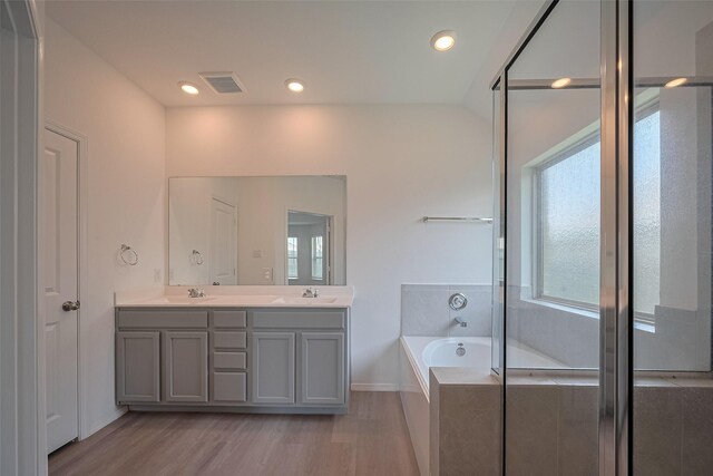 bathroom featuring a bath, wood finished floors, visible vents, and a sink