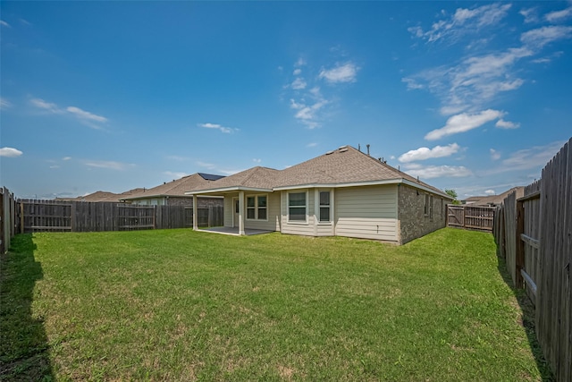 rear view of property featuring a fenced backyard, a patio, and a lawn