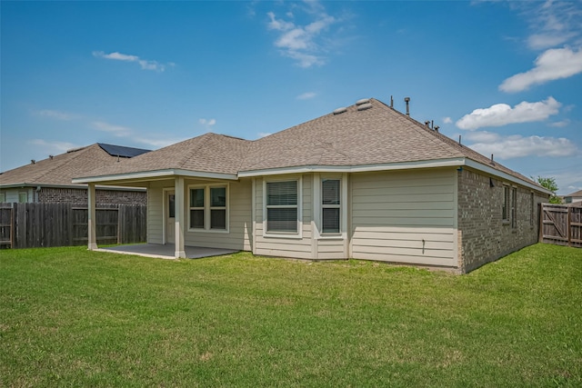 rear view of house with a fenced backyard, roof with shingles, a yard, and a patio area