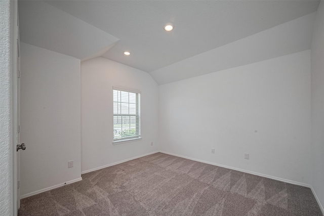 carpeted empty room with recessed lighting, lofted ceiling, and baseboards