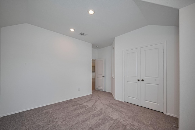 unfurnished bedroom featuring visible vents, vaulted ceiling, carpet flooring, and a closet