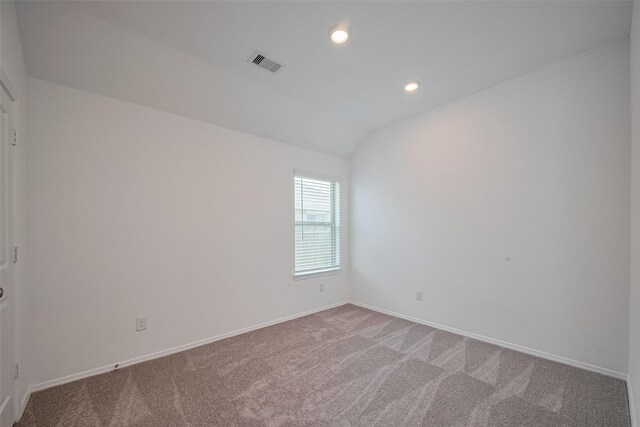 spare room with lofted ceiling, baseboards, visible vents, and carpet flooring