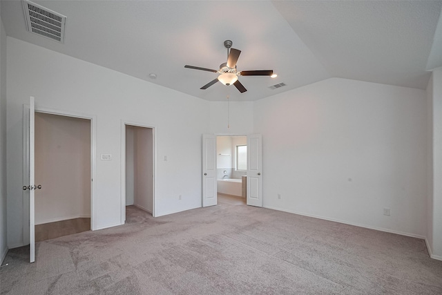 unfurnished bedroom featuring vaulted ceiling, visible vents, and light colored carpet