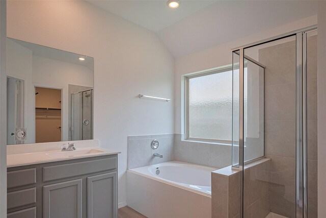 full bath featuring a bath, a stall shower, a spacious closet, lofted ceiling, and vanity