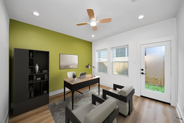 home office with plenty of natural light, a ceiling fan, baseboards, and light wood-style flooring