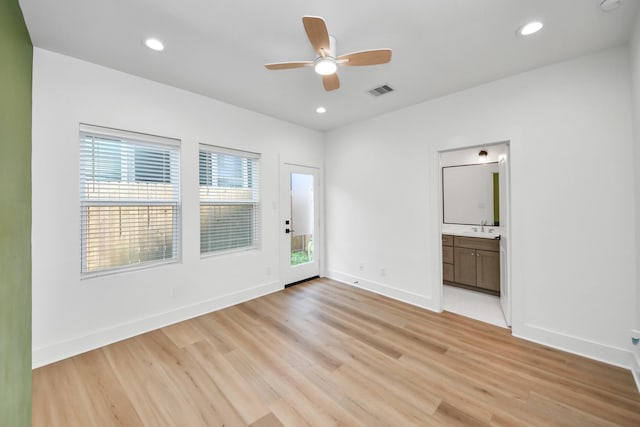 spare room with a sink, baseboards, visible vents, light wood-style floors, and a ceiling fan