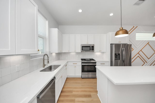 kitchen featuring stainless steel appliances, light countertops, backsplash, visible vents, and a sink