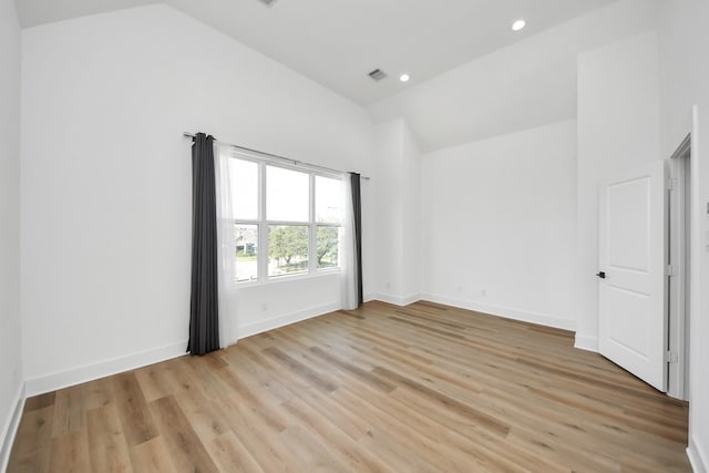 unfurnished room with light wood-type flooring, baseboards, recessed lighting, visible vents, and high vaulted ceiling