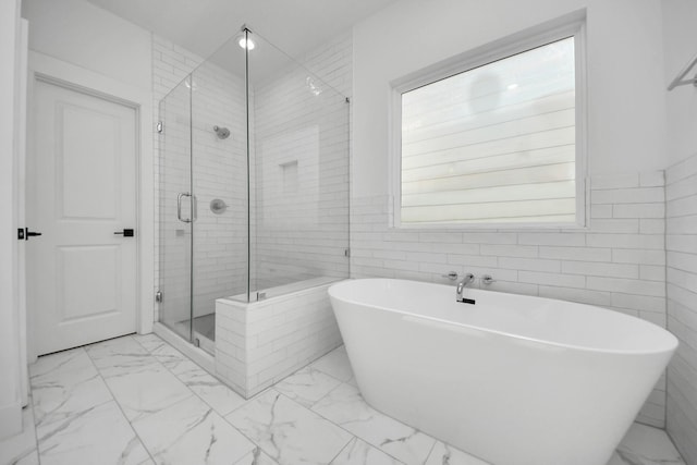 full bath featuring marble finish floor, a shower stall, and a freestanding bath