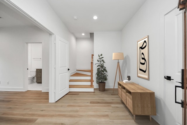 hallway with baseboards, recessed lighting, and light wood-style floors