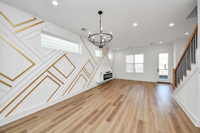 unfurnished living room featuring a chandelier, stairway, light wood-style flooring, and recessed lighting