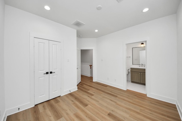unfurnished bedroom with a sink, a closet, light wood-type flooring, baseboards, and visible vents