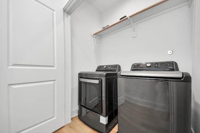 clothes washing area featuring washing machine and dryer, light wood-style floors, and laundry area