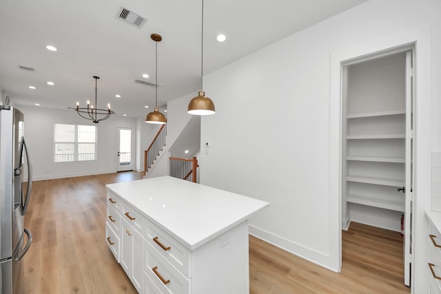 kitchen featuring white cabinets, freestanding refrigerator, visible vents, and light wood finished floors