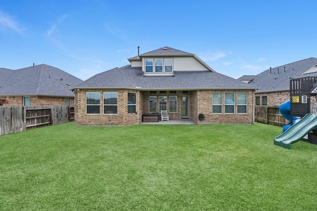 back of house with a shingled roof, a fenced backyard, a yard, a patio area, and brick siding