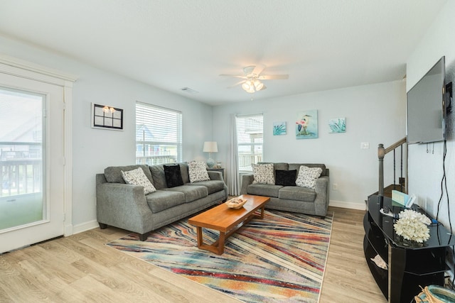 living room featuring light wood-type flooring, a ceiling fan, baseboards, and visible vents