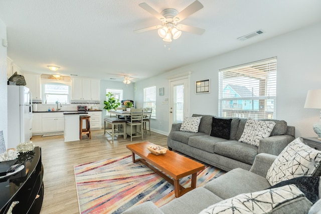 living area featuring a ceiling fan, light wood-style flooring, and visible vents