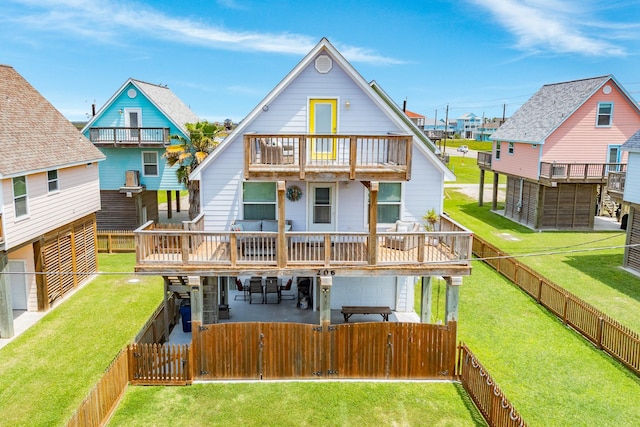 rear view of property featuring a fenced backyard, a gate, a balcony, a lawn, and a patio