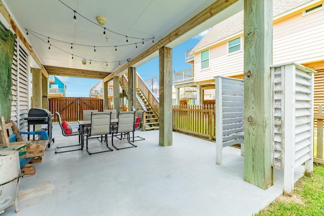 view of patio with fence, outdoor dining area, and stairs