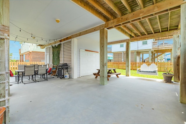 view of patio featuring outdoor dining area, an attached garage, fence, and a grill