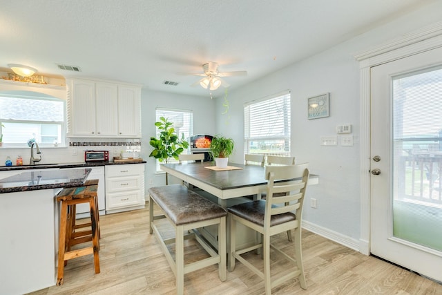 dining room with light wood-style floors, baseboards, ceiling fan, and visible vents