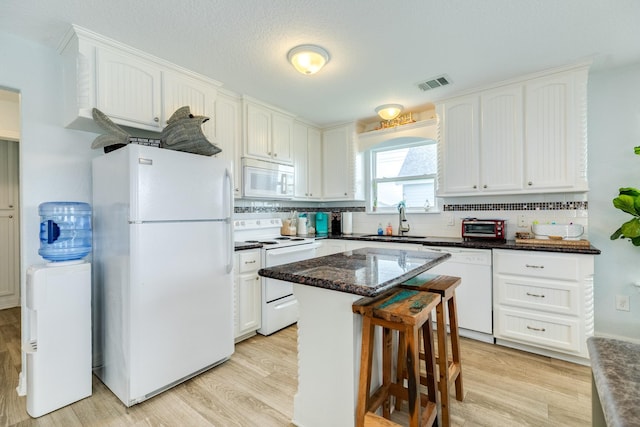 kitchen featuring white appliances, visible vents, a sink, and light wood-style floors