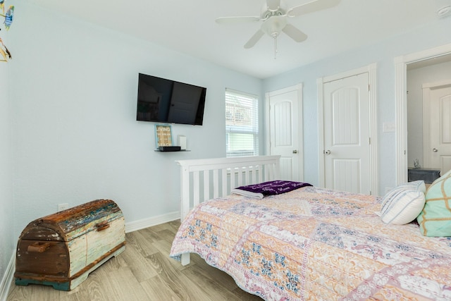 bedroom with baseboards, ceiling fan, two closets, and wood finished floors