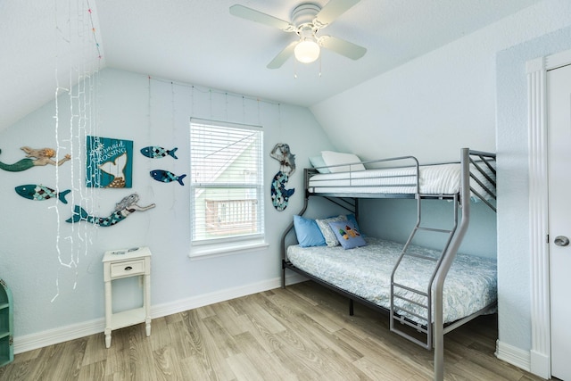 bedroom featuring baseboards, wood finished floors, and vaulted ceiling