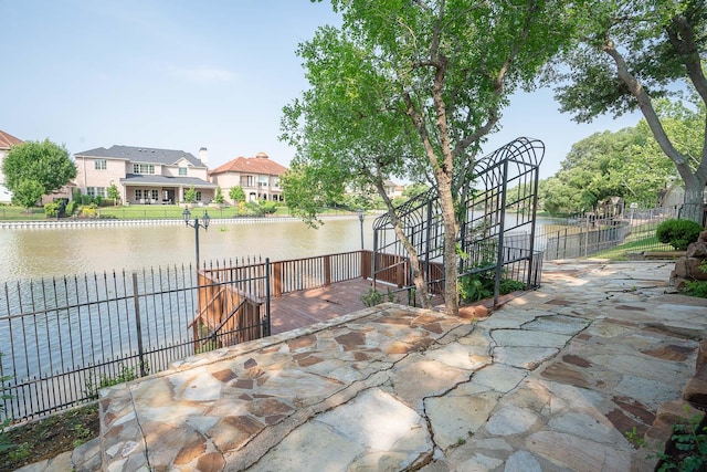 view of patio featuring fence and a water view