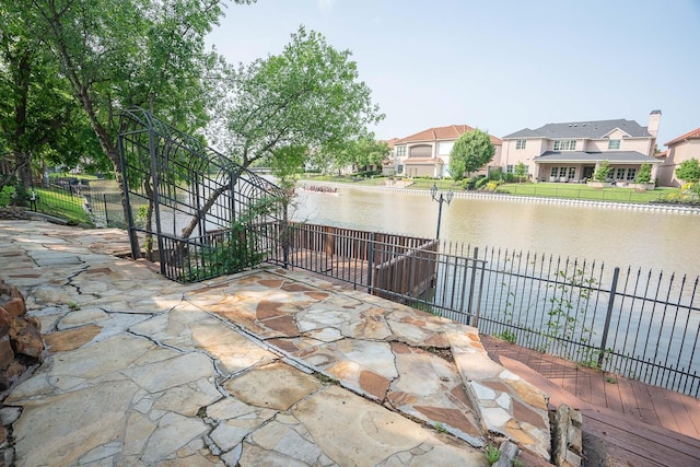 view of patio / terrace featuring a residential view, a water view, and fence
